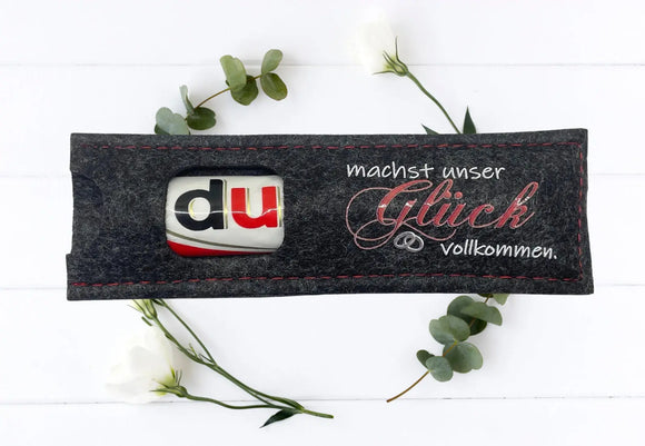 Zwei Filzhüllen in Hell- und Dunkelgrau mit Hochzeitsbotschaft „Glück vollkommen“ als Tischdeko