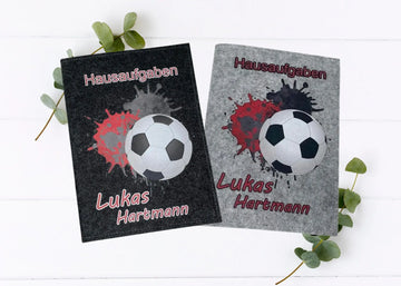 Zwei Filzhüllen für Hausaufgabenhefte mit Fußballmotiv und roten Farbspritzern.