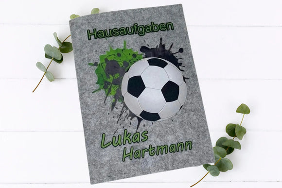 Zwei Varianten einer Heft-Hülle mit Fußballaufdruck – in Grau und Anthrazit.