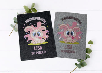 Zwei Filzhüllen für Hausaufgabenhefte mit lustigem Hasenmotiv auf grauem und schwarzem Hintergrund.