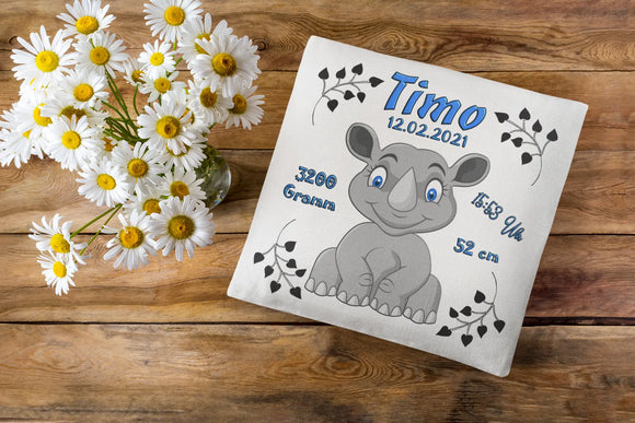 Baby-Kissen mit Nashorn und Geburtsangaben – süßes Tiermotiv in Grautönen auf weißem Hintergrund, kombiniert mit dekorativer Schrift und Blättern.