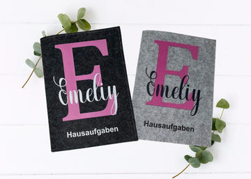 Zwei Filzhüllen für Hausaufgabenhefte mit großem violettem Initial und modernem Design.