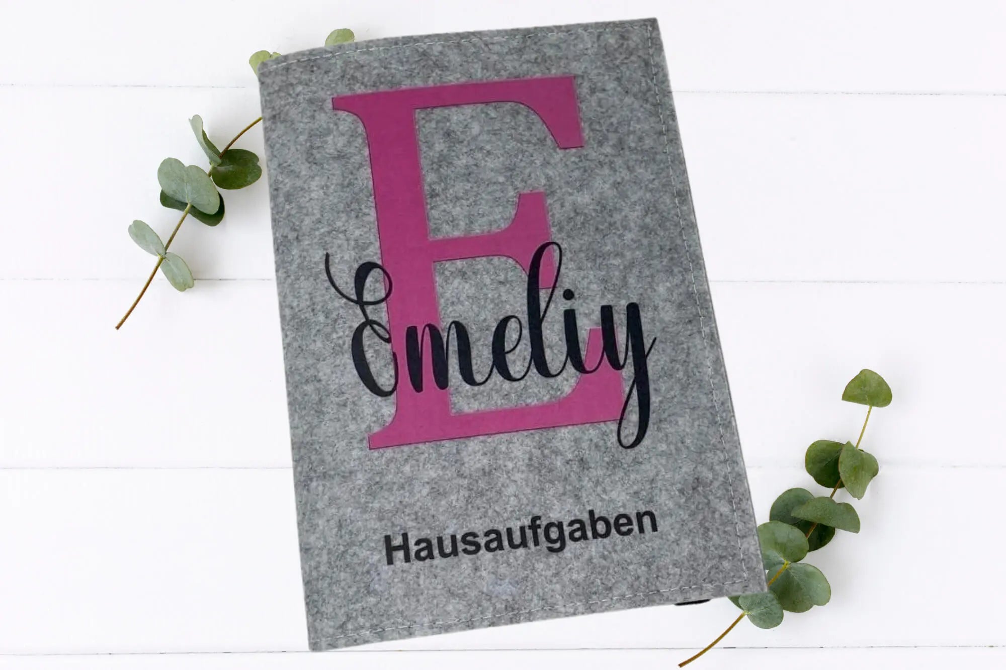 Hausaufgabenheft-Hüllen aus grauem und dunkelgrauem Filz mit lilafarbenem Buchstaben und eleganter Schrift.