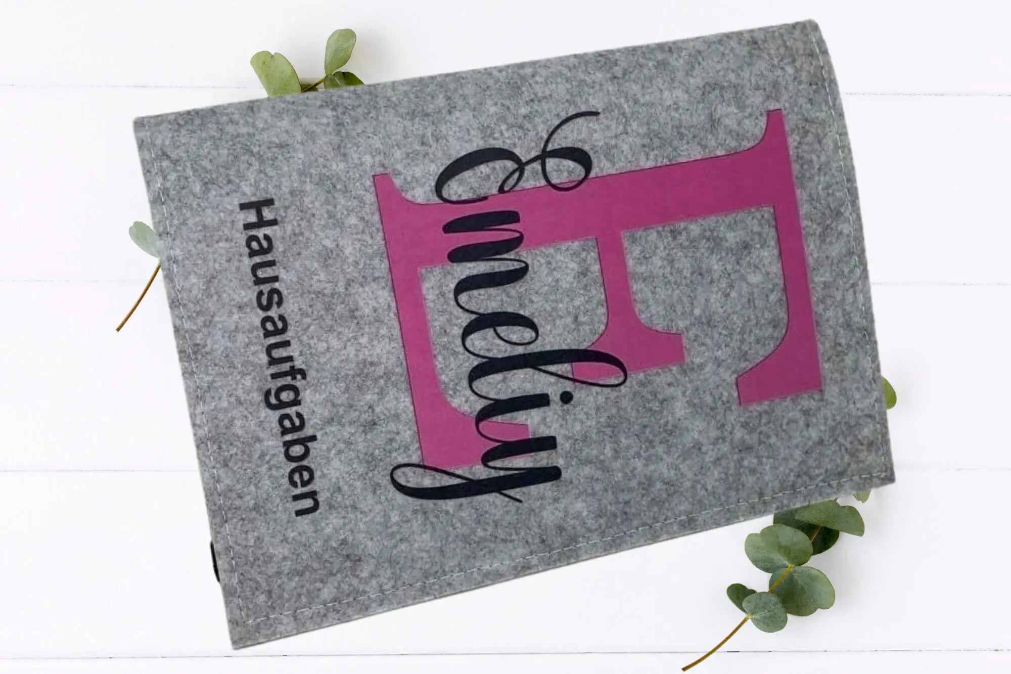 Filzhüllen für Schulkinder mit modernem Initial und Aufdruck „Hausaufgaben“.