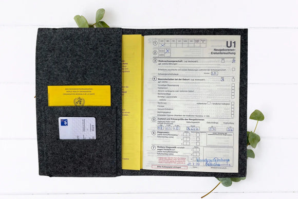 Verspielte U-Heft-Hülle aus grauem Filz mit Baby-Flusspferd und dunklen Herzpfoten.