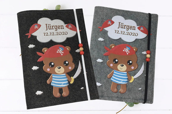 Filzhülle fürs U-Heft mit niedlichem Piratenbären in blau-weißem Shirt und rotem Kopftuch mit Totenkopf.