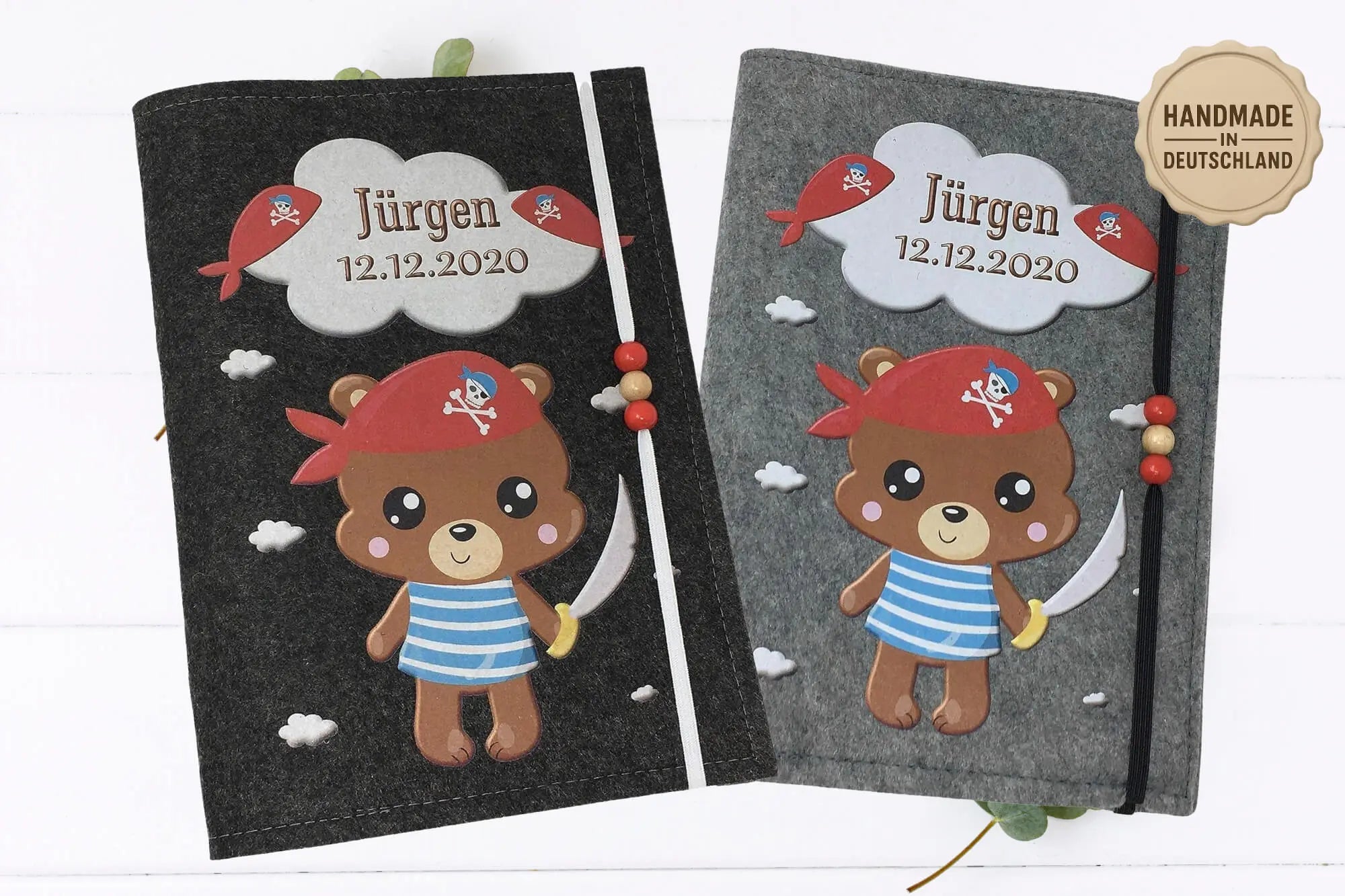 Graue U-Heft-Hülle mit Comicbär als Pirat, Schwert in der Hand und dekorativen Wolken-Elementen.