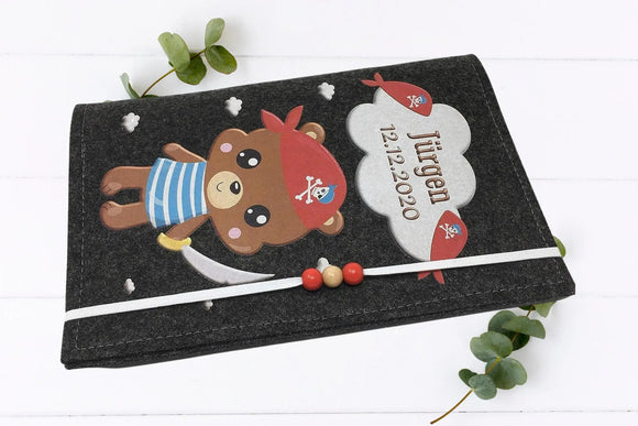 U-Heft-Hülle mit Piratenbär und Sprechblase für Namen und Geburtsdatum – aus robustem Filz gefertigt.