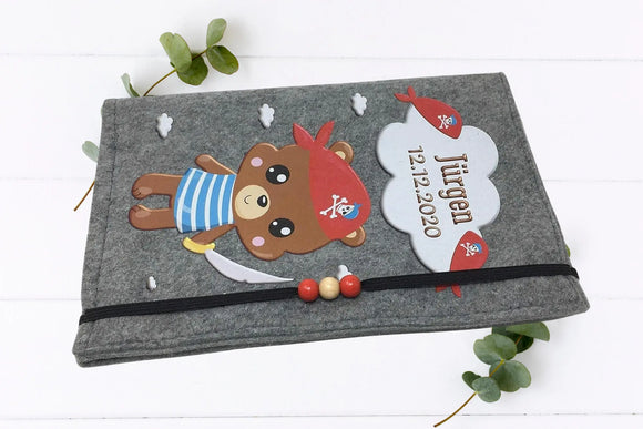 Niedlicher Piratenbär auf U-Heft-Hülle aus Filz – kindliches Design mit maritimen Details.