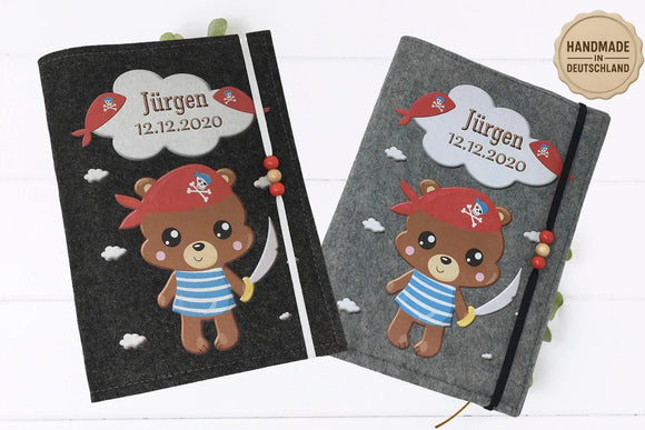 Graue Filzhülle für das U-Heft mit liebevoll illustriertem Piratenbären und Wolkenelementen.