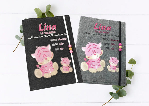 Personalisierte U-Heft-Hülle aus grauem Filz mit zwei niedlichen rosa Tigern und rosa Holzperlen.
