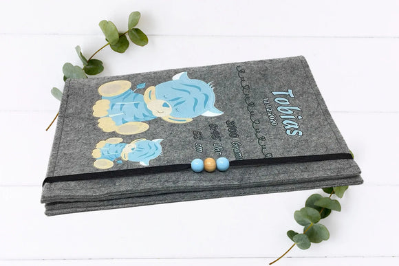 Personalisierte Hülle fürs U-Heft mit hellblauen Tigern und elastischem Verschluss mit Holzperlen.