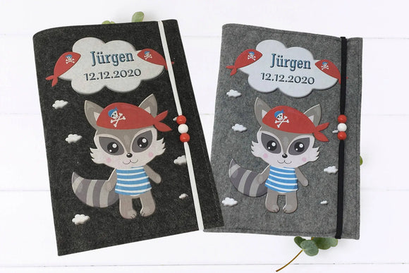 Filzhülle fürs U-Heft mit Waschbär im Seeräuber-Look, umgeben von kleinen weißen Wolken.