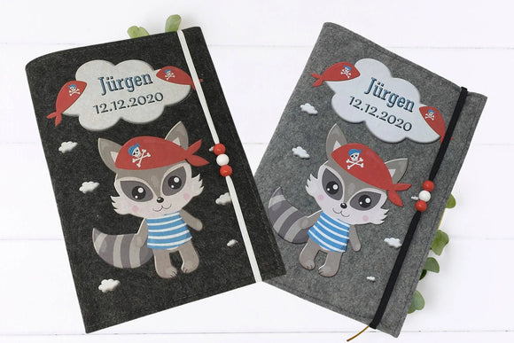 Illustrative U-Heft-Hülle mit fröhlichem Waschbären-Piratenmotiv – perfekt als Geschenk zur Geburt.