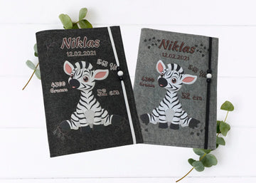 Personalisierte U-Heft-Hülle aus grauem Filz mit süßem Zebra-Motiv und Herzspur.