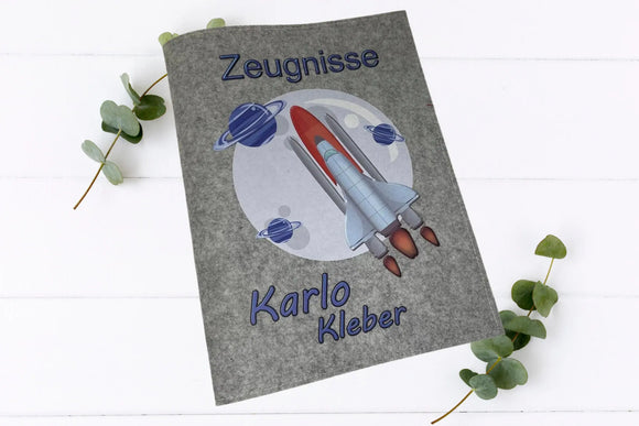 Personalisierte Schulzeugnismappe mit Raumfahrt-Design, Namensaufdruck und Planeten-Illustration auf grauem Filz