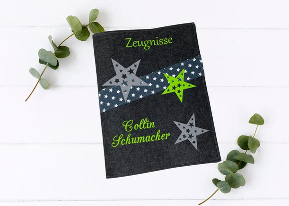Personalisierte Zeugnismappe aus dunkelgrauem Filz mit grünem Schriftzug, grauen und grünen Sternen sowie diagonalem Sternenband