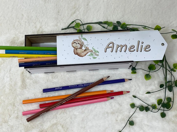 Holz-Stiftebox mit niedlichem Faultier-Motiv, gefüllt mit bunten Buntstiften auf weicher Unterlage