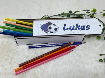 Personalisierte Stiftebox aus Holz mit Fußball-Motiv und blauer Beschriftung, gefüllt mit Buntstiften