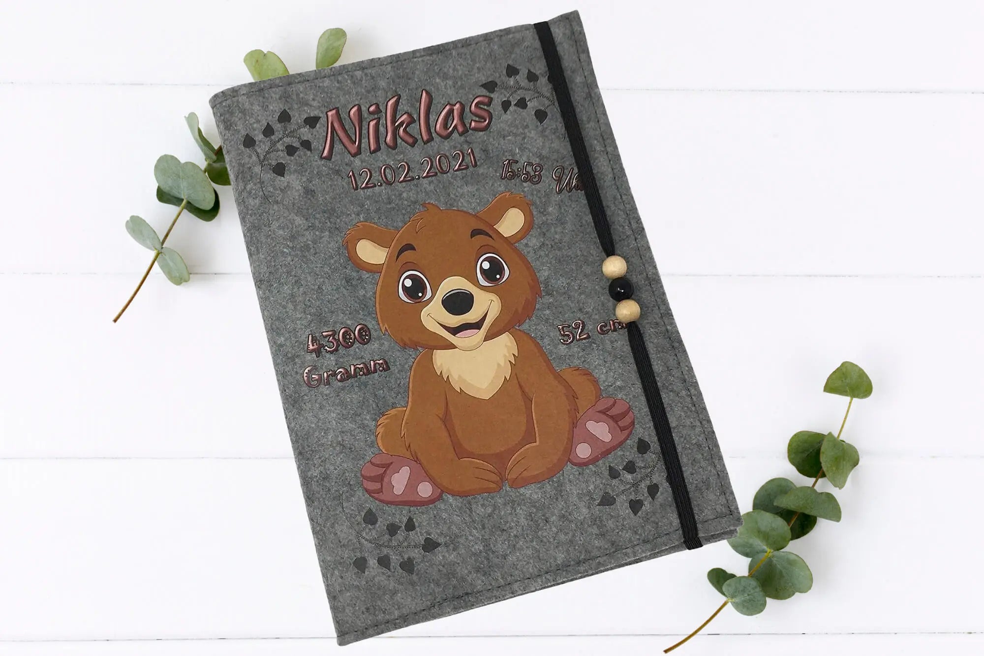 Kindgerechte U-Heft-Hülle mit fröhlichem Braunbär, rosa Tatzen und süßen Herzmustern auf Filz.