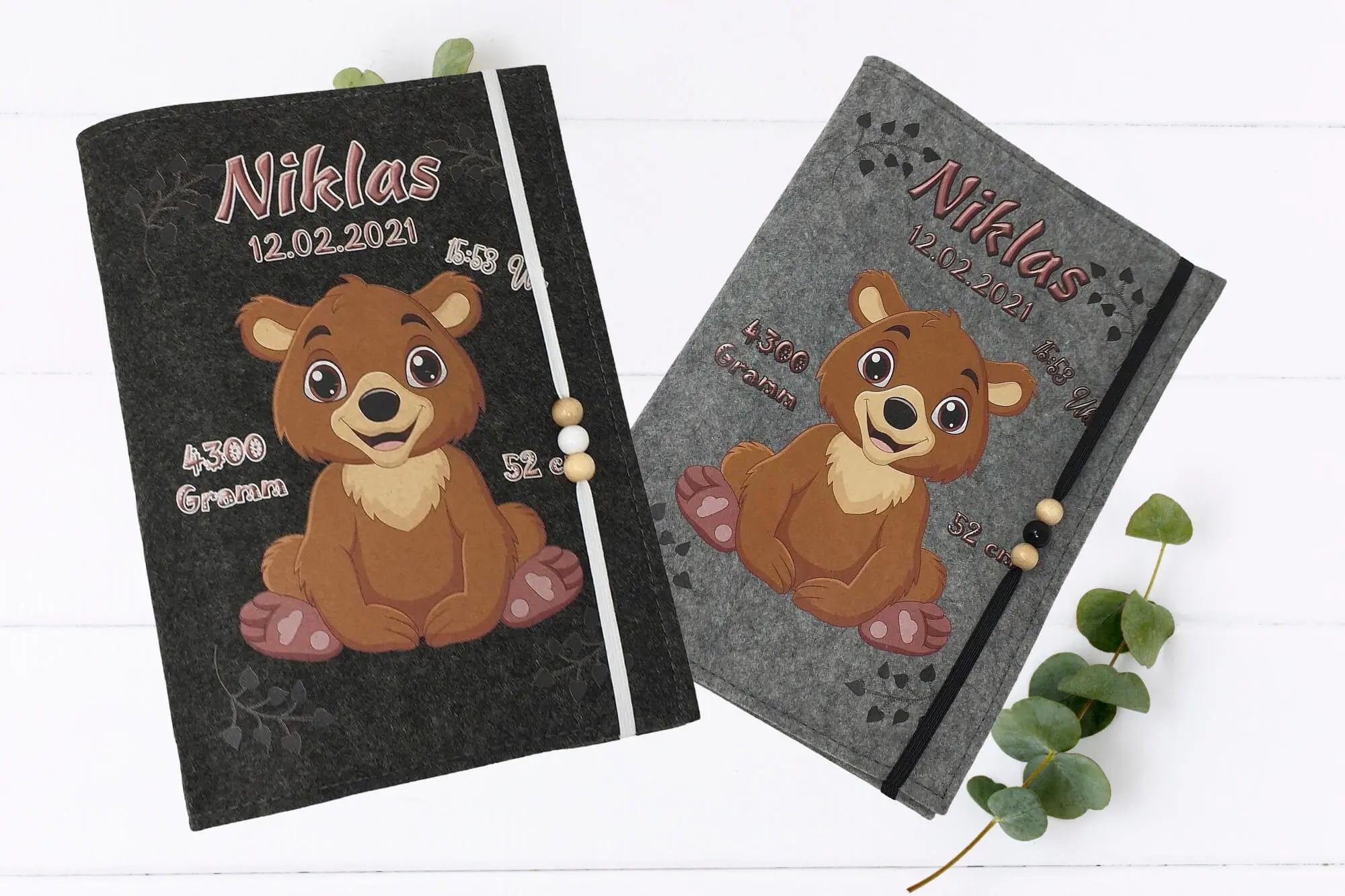 U-Heft-Hülle in Grau mit lachendem Bärchen und Fußspuren-Herzdekor – ideal als Geschenk zur Geburt.