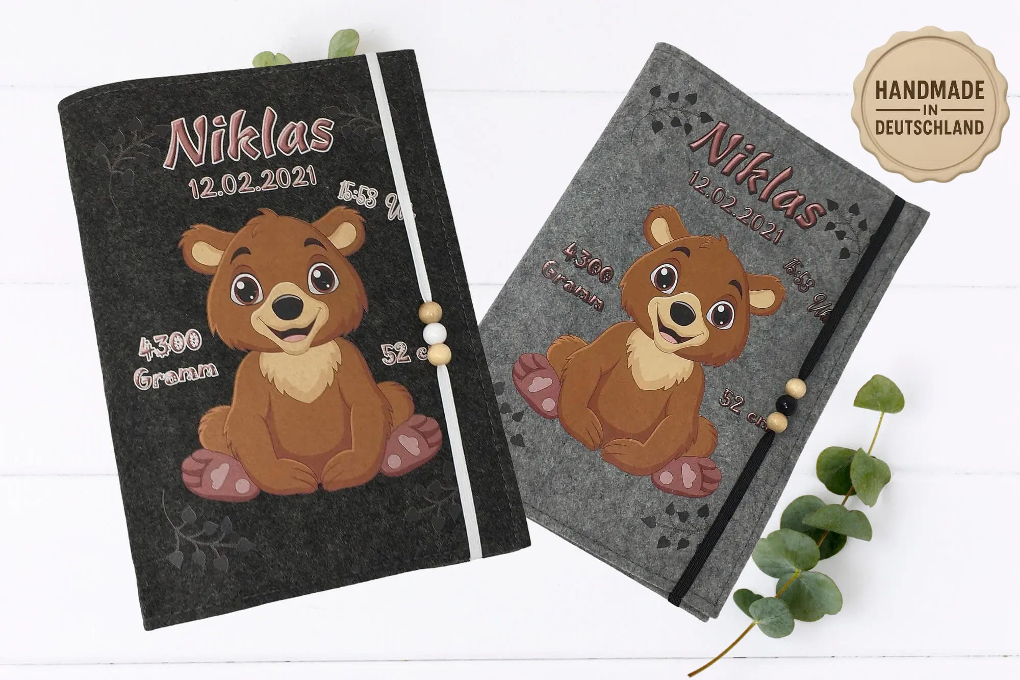Bärenstarkes Design auf U-Heft-Hülle: Babybär mit liebevollen Details wie Tatzenherzen und Holzperlenband.“