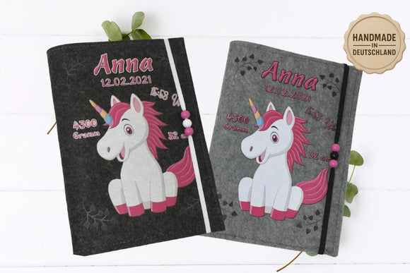 Graue U-Heft-Hülle mit sitzendem Einhorn in Rosa und Regenbogenfarben – ideal zur Geburt.