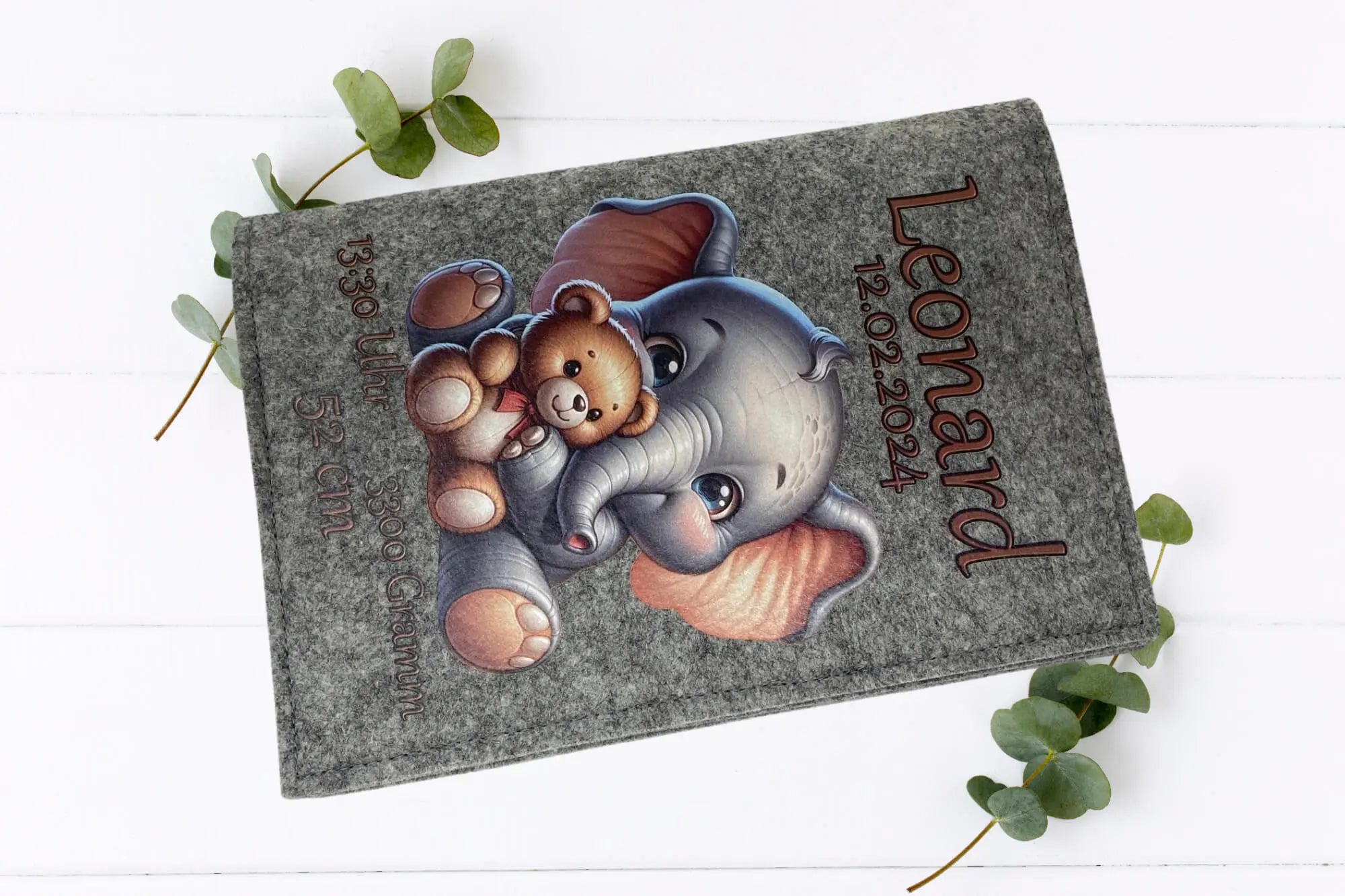 Zwei U-Heft-Hüllen mit identischem Motiv: niedlicher Elefant mit Teddybär auf hellgrauem und dunklem Filz.
