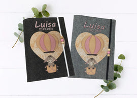 Personalisierte U-Heft-Hülle aus grauem Filz mit süßem Esel im rosafarbenen Heißluftballon.