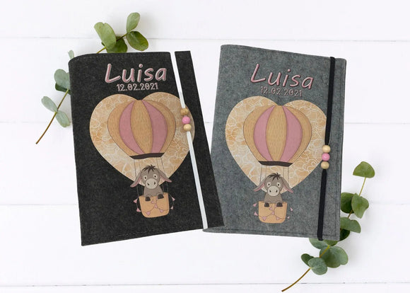 Personalisierte U-Heft-Hülle aus grauem Filz mit süßem Esel im rosafarbenen Heißluftballon.