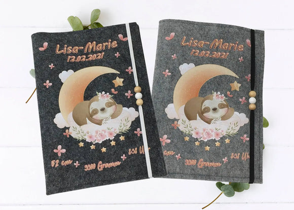 Personalisierte U-Heft-Hülle aus grauem Filz mit schlafendem Faultier auf Halbmond und Blumendekor.