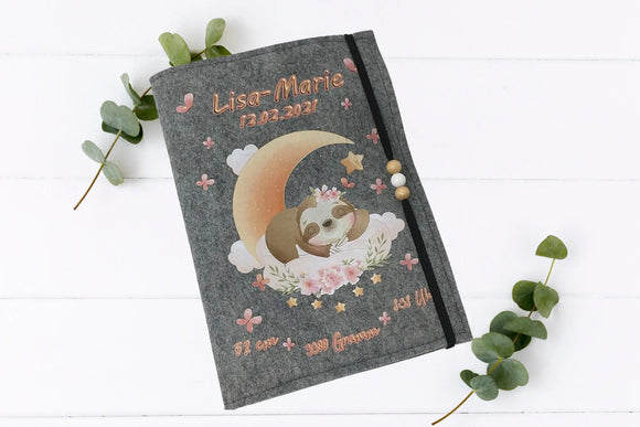 Zart illustrierte U-Heft-Hülle mit schlafendem Faultier auf Wolkenbett, Halbmond und Sternendekor.