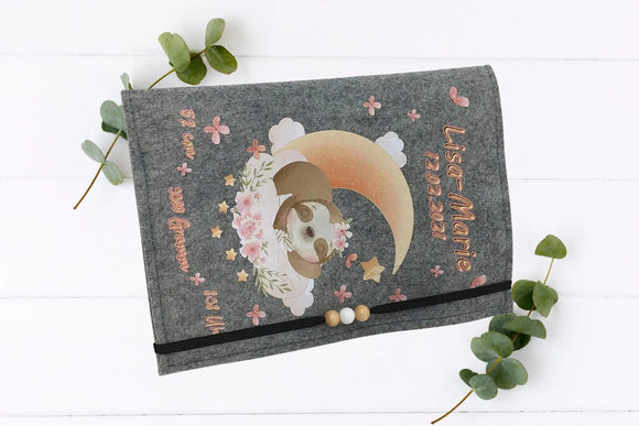 Handgemachte U-Heft-Hülle mit süßem Faultier, Blumenkranz, fliegenden Schmetterlingen und Mondmotiv.