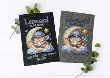 Personalisierte U-Heft-Hülle aus grauem Filz mit schlafender Giraffe auf Mondsichel und umgeben von Sternen.