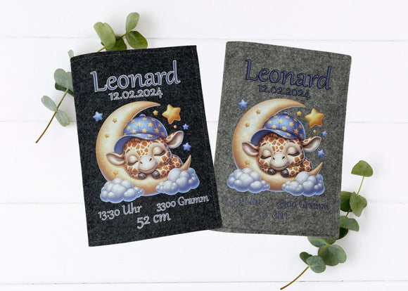 Personalisierte U-Heft-Hülle aus grauem Filz mit schlafender Giraffe auf Mondsichel und umgeben von Sternen.