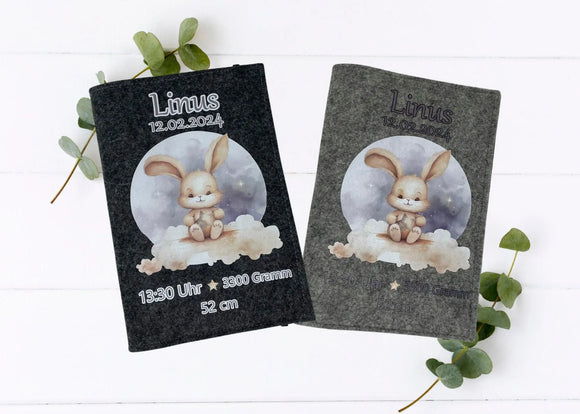 Personalisierte U-Heft-Hülle aus grauem Filz mit süßem Häschen auf einer Wolke vor nächtlichem Himmel.