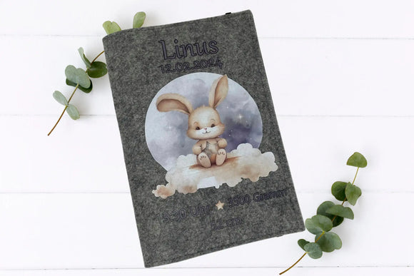 Graue Filzhülle fürs U-Heft mit Hasenbaby auf einer weichen Wolke unter dem Sternenhimmel.