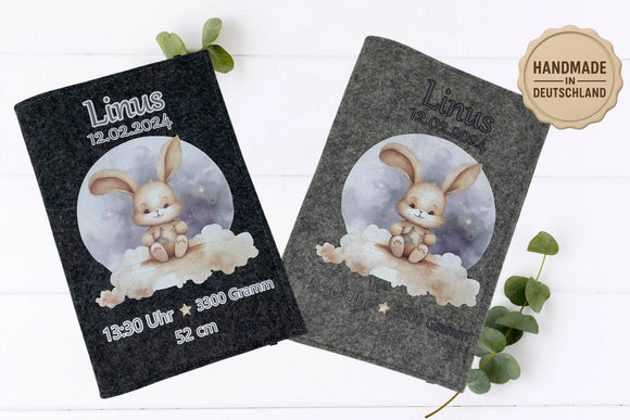 Liebevoll illustrierte U-Heft-Hülle mit Hase unter Sternenhimmel – sanfte Farbtöne auf grauem Filz.