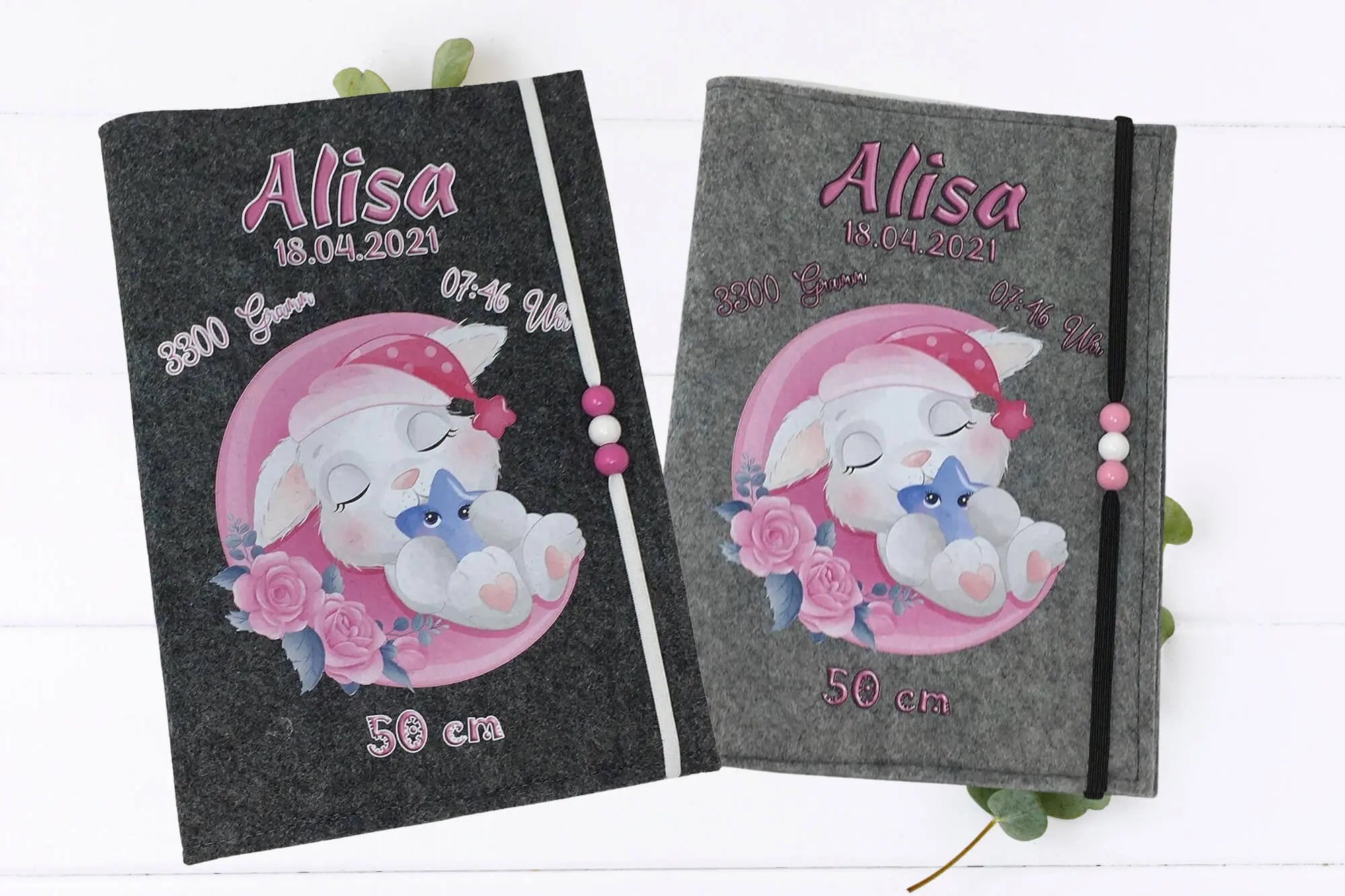 Babyhase mit geschlossenen Augen und rosa Accessoires – U-Heft-Hülle mit zartem Design.