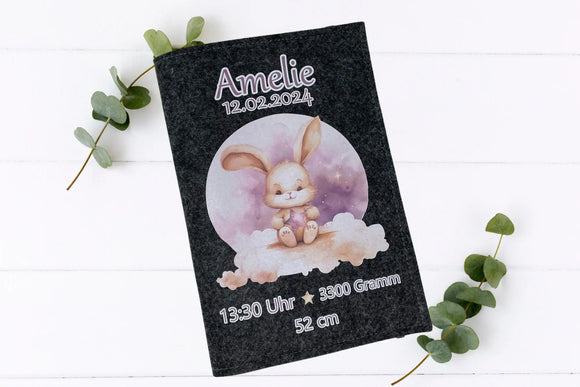 Graue Filzhülle mit niedlichem Hasenbaby auf weicher Wolke und sanftem Himmel in Rosatönen