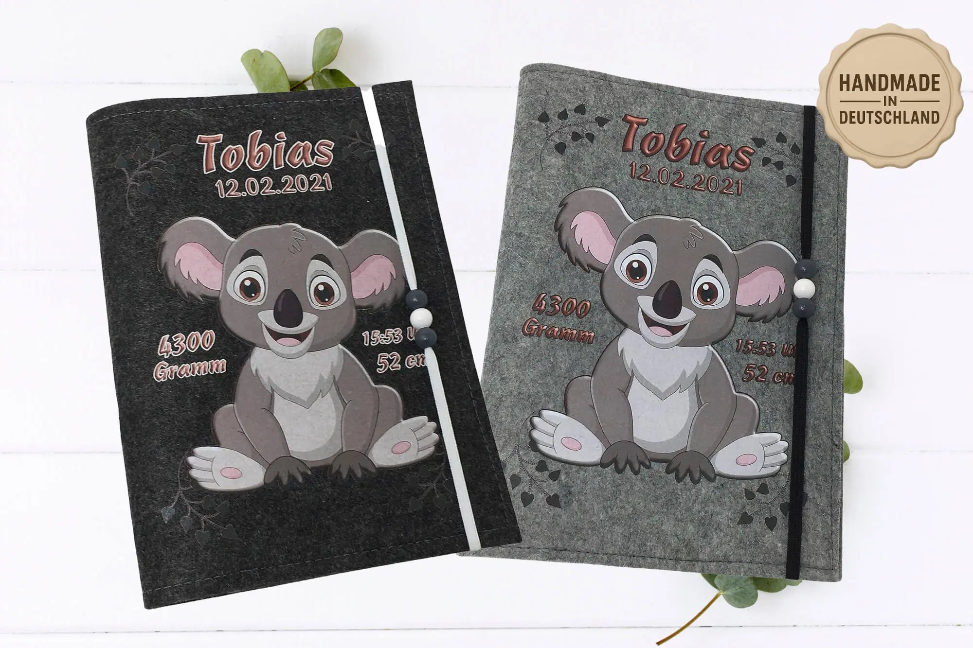 Graue Filzhülle mit Koala-Illustration und elastischem Band mit Perlen in Weiß und Grau.