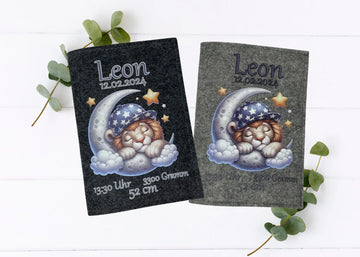 Personalisierte U-Heft-Hülle aus grauem Filz mit schlafendem Löwen auf einem Halbmond und Sternenhimmel.