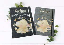 Personalisierte U-Heft-Hülle aus grauem Filz mit schlafendem Löwenbaby und zarten Blumen.