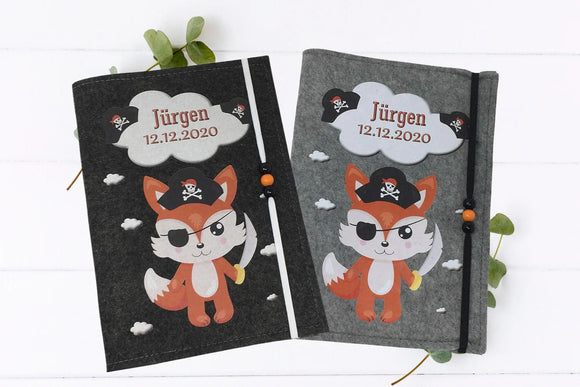 U-Heft-Hülle mit niedlichem Piratenfuchs, schwarzem Hut mit Totenkopf und orangefarbenen Holzperlen.