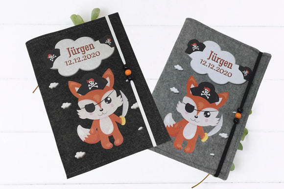 Verspielte U-Heft-Hülle mit rotem Fuchs in Piratenoutfit – ideal als personalisiertes Geburtsgeschenk.