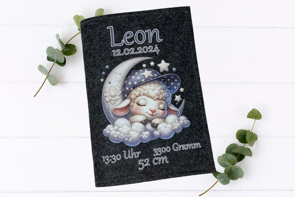Graue Filzhülle fürs U-Heft mit verträumtem Schaf, Mondmotiv und Sternen – inklusive Geburtsangaben.