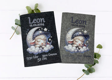 Personalisierte U-Heft-Hülle aus grauem Filz mit schlafendem Schäfchen auf Mondsichel und Sternenhimmel.