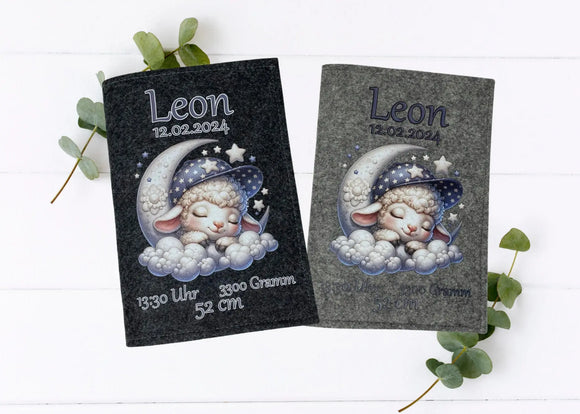 Personalisierte U-Heft-Hülle aus grauem Filz mit schlafendem Schäfchen auf Mondsichel und Sternenhimmel.