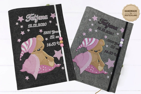 U-Heft-Hülle mit niedlichem Bärenbaby in rosa Schlafmütze und Decke, umgeben von Sternen.