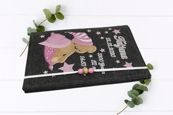 Rosa Sternendesign mit schlafendem Teddybär auf U-Heft-Hülle aus grauem Filz – ideal zur Geburt.